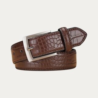 Ceinture simili-cuir effet crocodile pour homme marron enroulé sur elle et mettant en évidence sa boucle métallique sur fond uni.
