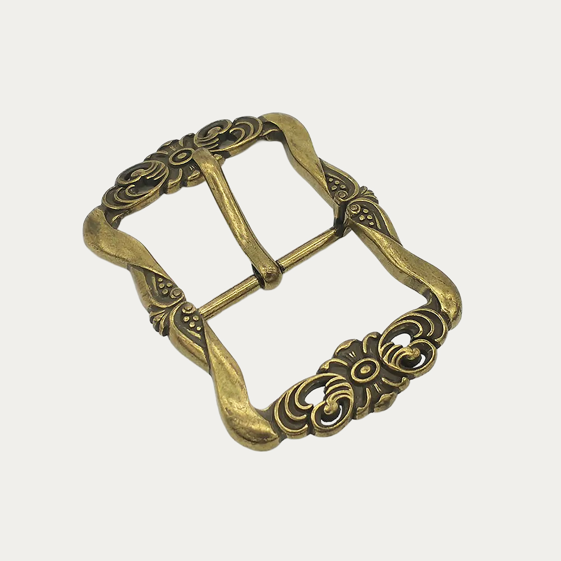 Une boucle ceinture femme avec motifs floraux sculptés de couleur dorée sur un fond gris très clair uni.
